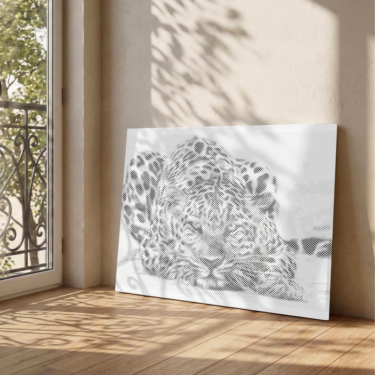 A large rectangular dot art painting leaning against a beige wall on a wooden floor, showing a black-and-white leopard illustration. Sunlight and leaf shadows fall across the wall and floor, and glass doors with outdoor greenery are visible on the left.
