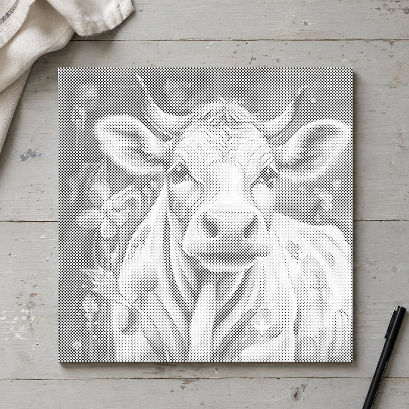 Toile de peinture par points “Vache joyeuse”, vue du dessus sur une table de travail à la lumière douce du jour.