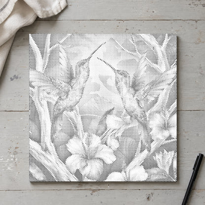 Toile de peinture par points “Colibris parmi les fleurs”, vue du dessus sur une table de travail à la lumière douce du jour.