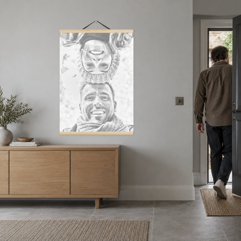 Cadre magnétique pour toile, sur le mur gris clair d’une entrée, avec une personne dans l’encadrement de la porte.