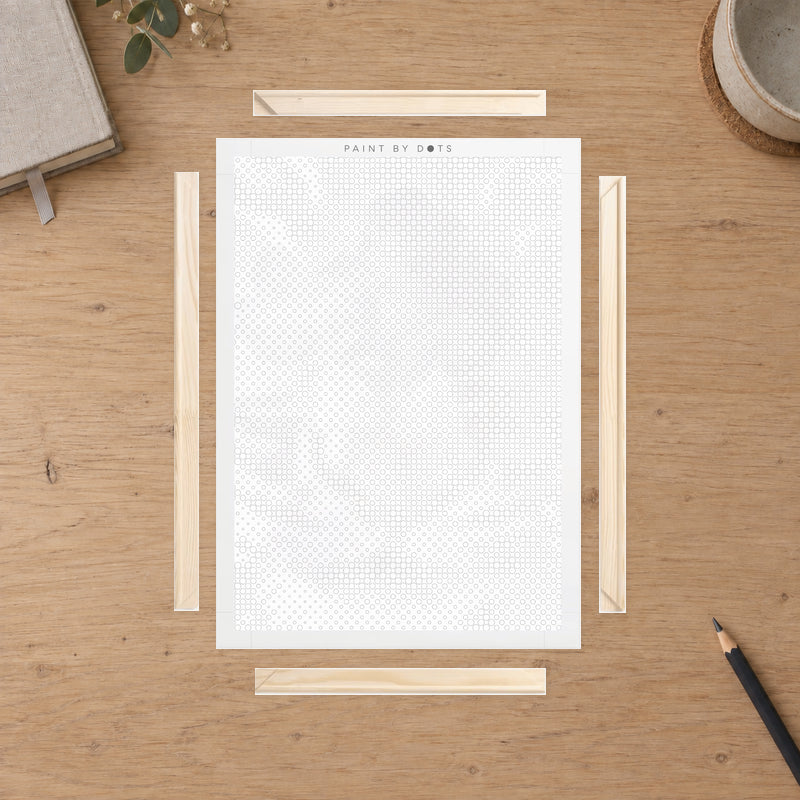 Kit cadre en bois pour toile, présenté sur une table de travail en chêne clair à la lumière du jour.